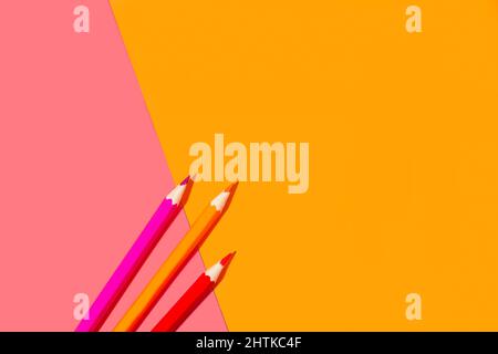 Orange and pink pencils on a pink and orange background in a top view Stock Photo
