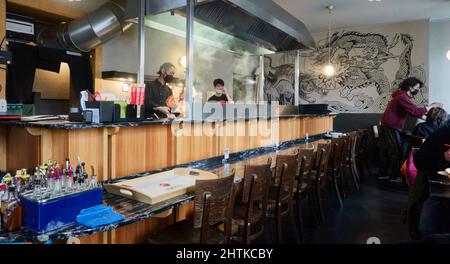 Berlin, Germany, February 26, 2022: Counter with stove behind it and cooks in a japanese noodle restaurant in Kreuzberg Stock Photo