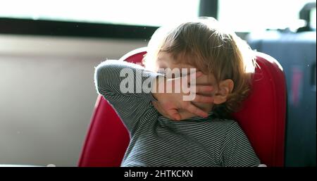 Allergic toddler wiping nose with sleeve and hand. Child wipes running nose Stock Photo