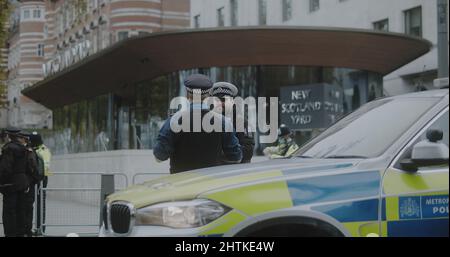 London, UK - 11 20 2021:  Two police officers on duty talking outside New Scotland Yard on Victoria Embankment, for an Insulate Britain protest. Stock Photo