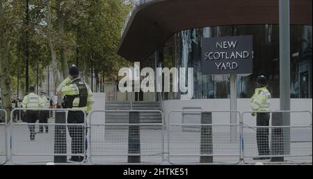 London, UK - 11 20 2021:  Police officers wearing face masks outside New Scotland Yard headquarters building on Victoria Embankment. Stock Photo