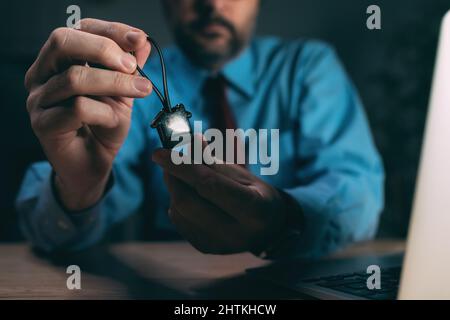 Shady real estate agent concept, broker in dark office with house shaped keychain, selective focus Stock Photo