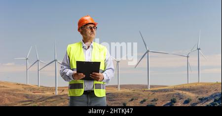 Mature engineer standing on a wind turbine farm and looking away Stock Photo