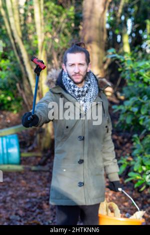 A close of of a discarded shotgun cartridge being being held by a young man that has collected it on a litter pick. Litter pick, rubbish, environmenta Stock Photo
