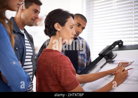 Showing the students how its done. Shot of a group of young designers working together in an office. Stock Photo
