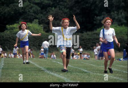primary school sports day, girls in running race with bean bags on heads Stock Photo