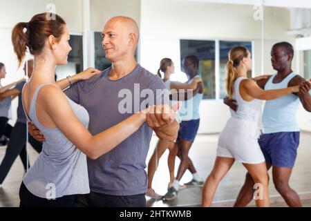 Young positive people dancing together slow ballroom dances in pairs Stock Photo