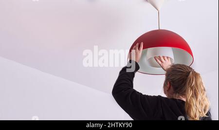 unrecognizable blonde woman changing a light bulb at home, DIY Stock Photo
