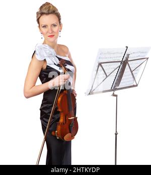 Beauty and baroque. A gorgeous violinist standing in front of a sheet music stand - portrait. Stock Photo