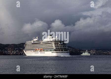 Cruise ship Viking Venus at Byfjorden, departing from port of Bergen, Norway. Dutch navy frigate F362 HDMS Peter Willemoes in background Stock Photo