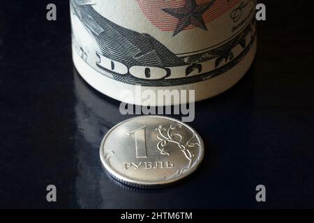 Russian ruble coin and dollar bills roll, ruble money is under pressure from geopolitics. Concept of ruble devaluation, inflation in Russia, economy f Stock Photo
