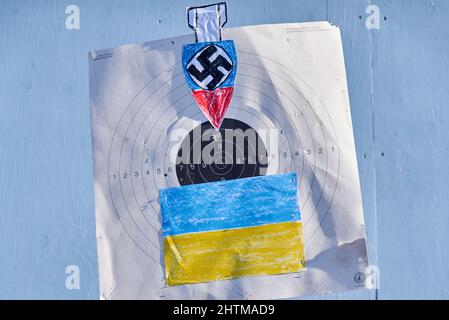 Helsinki, Finland - February 26, 2022: Sign with a shooting target, bomb & swastika and Ukrainian flag in a rally against Russia’s military aggression Stock Photo