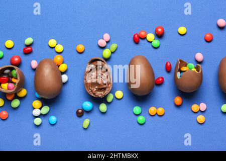 Delicious chocolate eggs with different fillings on blue background Stock Photo