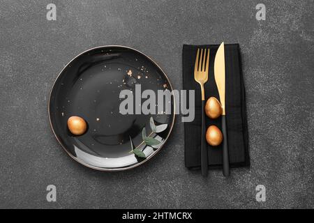 Table setting with Easter eggs and eucalyptus branch on dark background Stock Photo