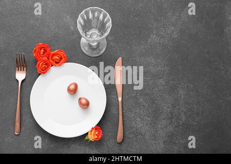 Table setting with Easter eggs and roses on dark background Stock Photo