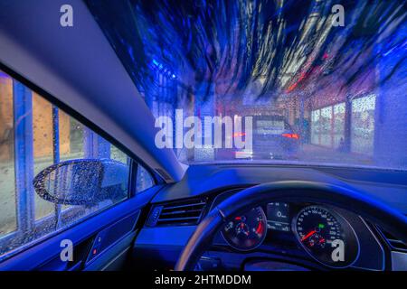 Car in an automatic car wash, car wash line, cleaning foam is sprayed on, rotating brushes clean the vehicle, Stock Photo