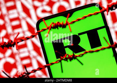 Smartphone with RT (Russia Today) logo on background of inscription censored behind barbed wire Stock Photo