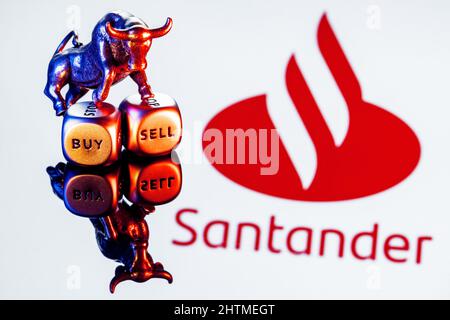 Metal bull stands on buy-sell dices on background of Santander bank logo Stock Photo