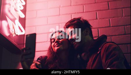 This is a night to remember. Shot of a young couple taking a selfie while standing outside a building at night. Stock Photo