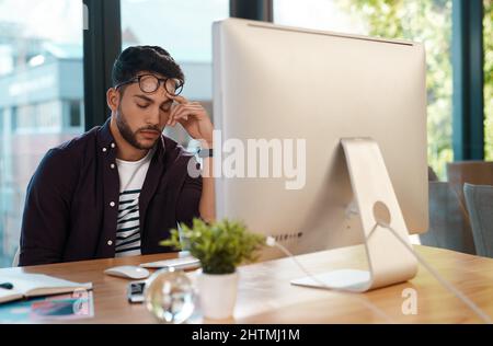 So sleepy. Cropped shot of a handsome young businessman feeling overwhelmed and falling asleep while sitting at his computer in his office. Stock Photo