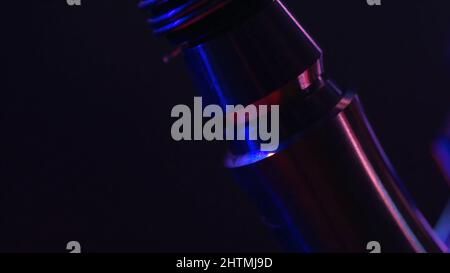 Close up of hookah metal details on black background with red and blue lights and smoke. Details of a man making hookah in smoke and neon light of nig Stock Photo