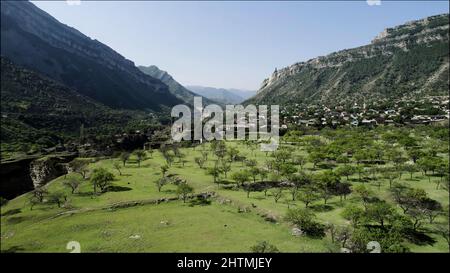 Old authentic village between two giant mountains. Action. Aerial view of a small town located in the valley between rocks on a summer sunny day Stock Photo