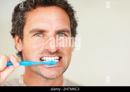 Handsome man brushing teeth. Closeup of handsome mature man brushing his teeth. Stock Photo
