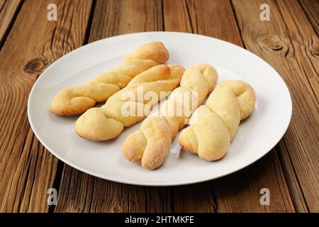 Twisted cookies on white plate on old wooden table closeup Stock Photo
