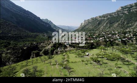 Old authentic village between two giant mountains. Action. Aerial view of a small town located in the valley between rocks on a summer sunny day Stock Photo