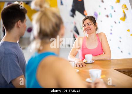 Woman chatting with friends at bar counter in climbing club during coffee break Stock Photo