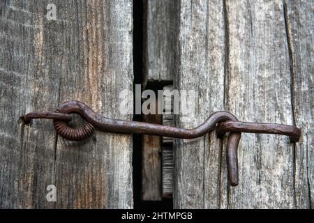 hook lock latched to bent nail on a wood door Stock Photo