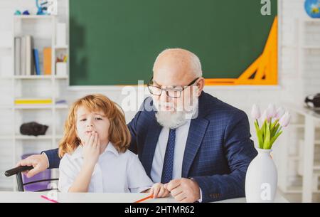 Teacher and school boy doing homework assignment at school. Stock Photo