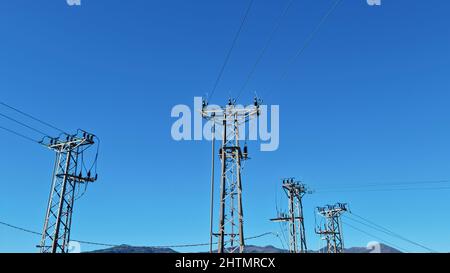 High voltage pylons over clear blue sky,electrical energy power infrastructure Stock Photo