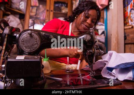 An African seamstress sews a dress with her sewing machine. Working female in her tailor shop Stock Photo