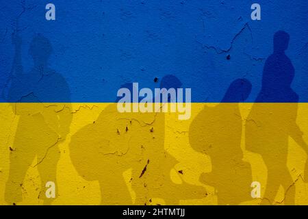 Ukraine flag on wall and shadows of soldier and refugees leaving. Ukraine war concept Stock Photo