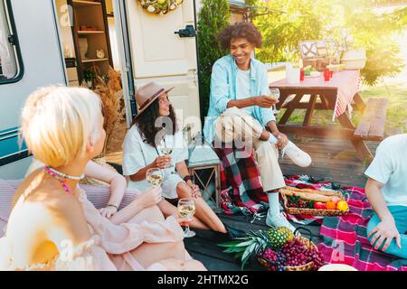 Friends have a picnic with a camper in a green meadow Stock Photo