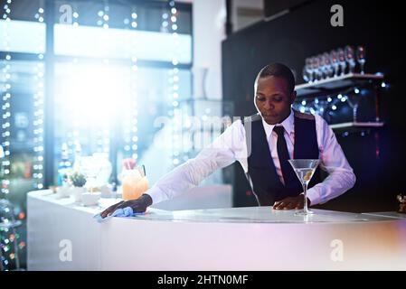 Hes always neat and have a pleasant appearance. Cropped shot of a well-dressed bartender standing behind the counter. Stock Photo