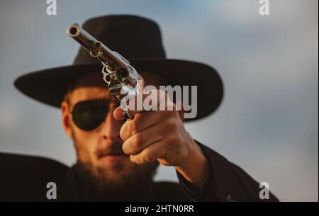 Cowboy shooter in black suit and cowboy hat. Serious man with wild west guns, retro pistol revolver and marshal ammunition. American western Sheriff Stock Photo