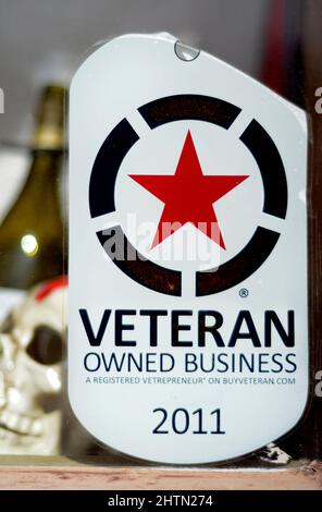 A sign in a store window identifies the business as owned by a US military veteran. Stock Photo