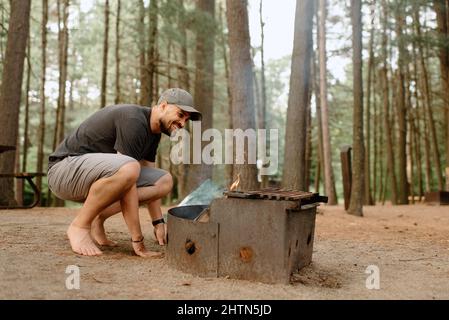 Canada, Yukon, Whitehorse, Man making fire on fire pit in campsite Stock Photo