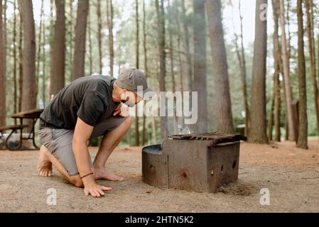 Canada, Yukon, Whitehorse, Man making fire on fire pit in campsite Stock Photo