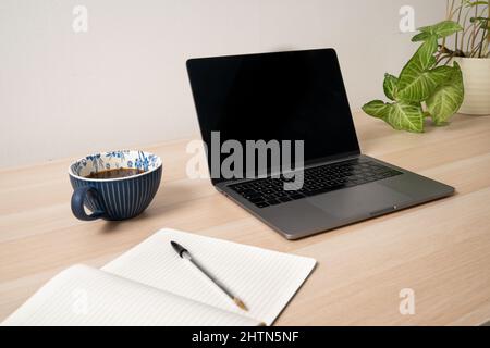 Laptop, notepad and coffee on desk Stock Photo