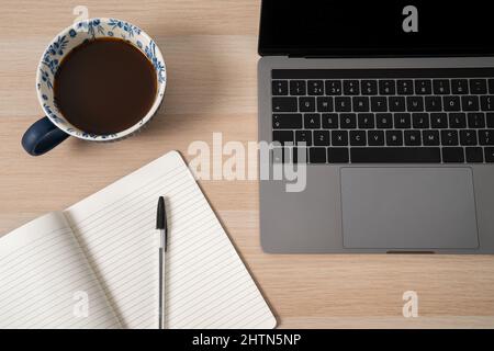 Laptop, notepad and coffee on desk Stock Photo