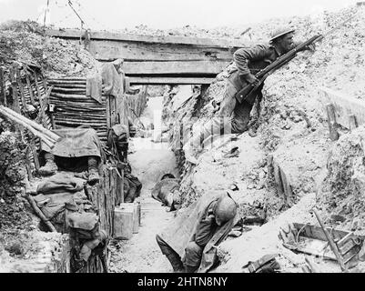 Soldiers of 'A' Company, 11th Battalion, the Cheshire Regiment, occupy a captured German trench at Ovillers-la-Boisselle on the Somme. In this photograph one man keeps sentry duty, looking over the parados and using an improvised fire step cut into the back slope of the trench, while his comrades rest. Stock Photo