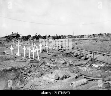 A group of german war graves with German shells in wicker carriers and a wrecked railway line in the foreground. A transport wagon is going towards the line in background. Northern corner of Bernafay Wood. September 1916. Stock Photo