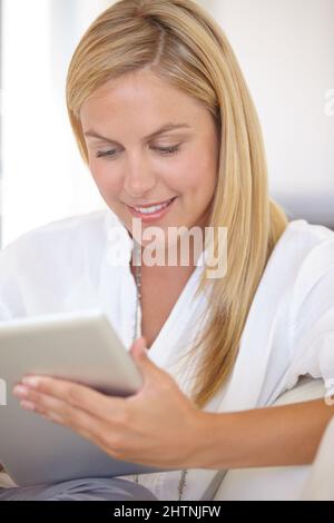Checking her work schedule. A beautiful young blonde woman working on her digital touchpad. Stock Photo