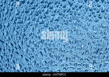 Blue decorative glass with a relief embossed pattern in the form of small pits or grooves. Glass glare background, texture. Color of the year 2020 con Stock Photo