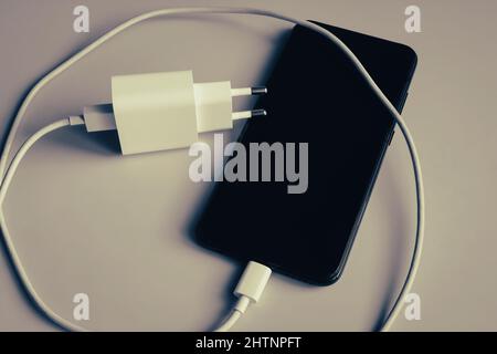 Charger with USB type C cable and smartphone in grunge style Stock Photo