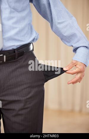 Underpaid. A cropped image of a businessman turning out his pocket and showing that it is empty. Stock Photo