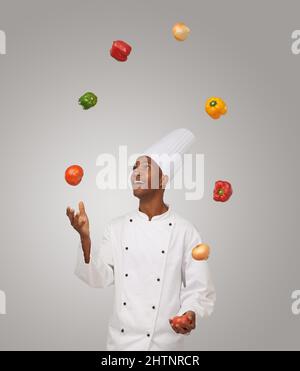 Tricks of the trade. A young African-American chef juggling with vegetables. Stock Photo